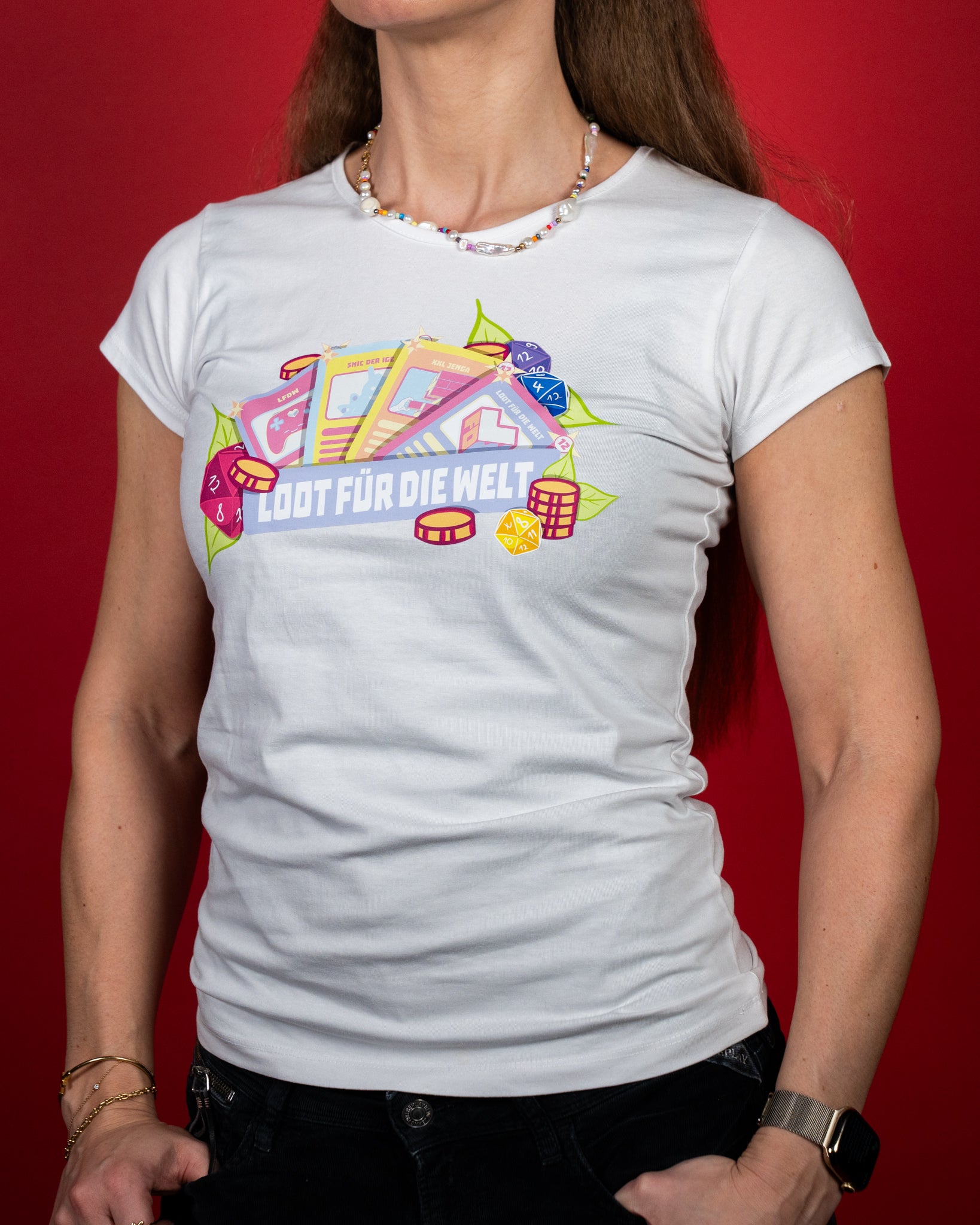 Weißes, tailliert geschnittenes T-Shirt aus weicher Baumwolle mit farbenfrohem Frontprint. Das Motiv zeigt Spielkarten, Würfel und Chips um den Schriftzug „LOOT FÜR DIE WELT“. Die Illustration kombiniert Rosa-, Gelb- und Blautöne mit grünen Blättern und steht im Mittelpunkt des Designs.