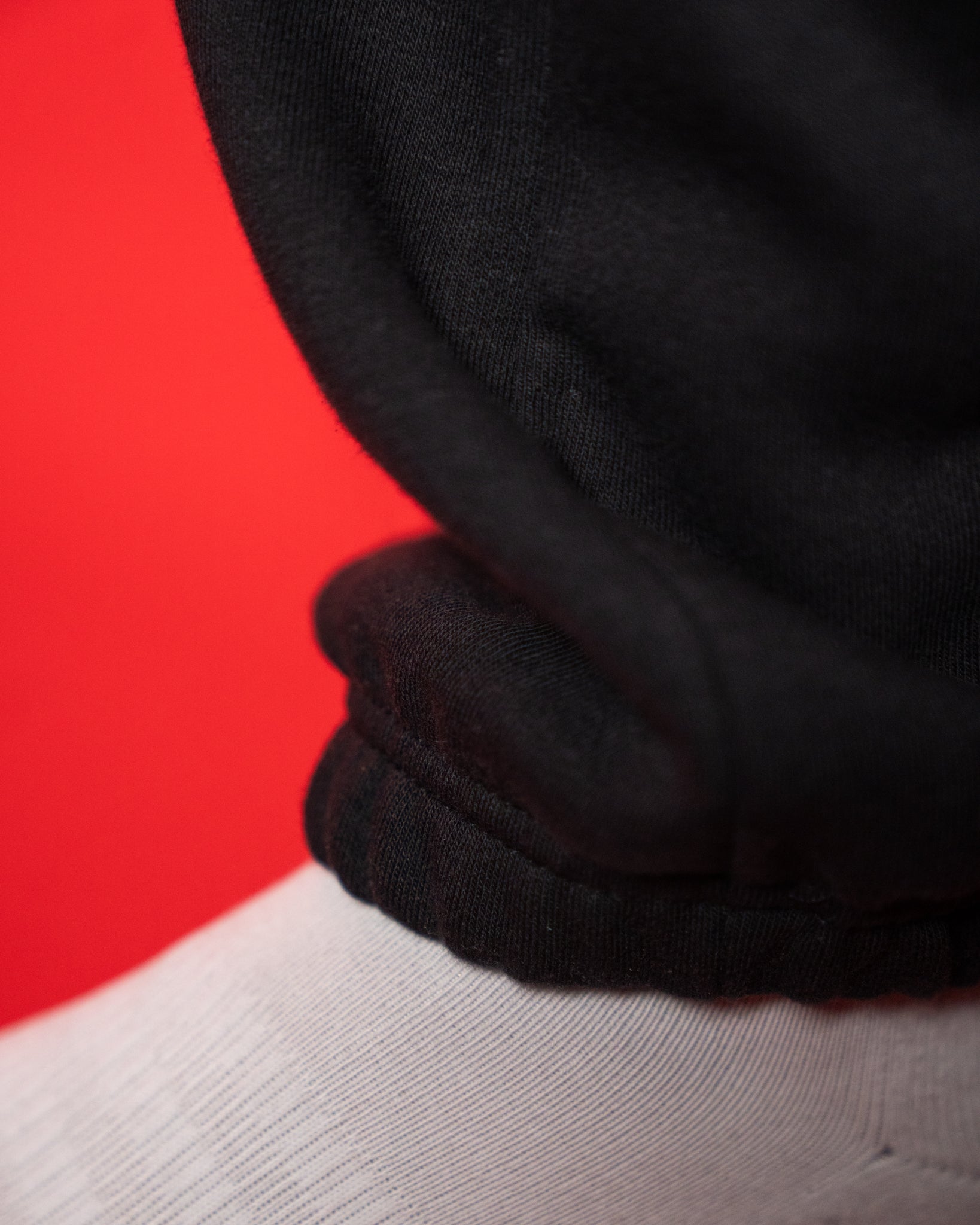 Nahaufnahme des Beinabschlusses einer schwarzen Jogginghose. Der elastische Saum liegt locker auf einer weißen Socke und zeigt die weiche, leicht strukturierte Stoffoberfläche. Das Detailfoto hebt die hochwertige Verarbeitung und den bequemen Sitz der Bündchen hervor.