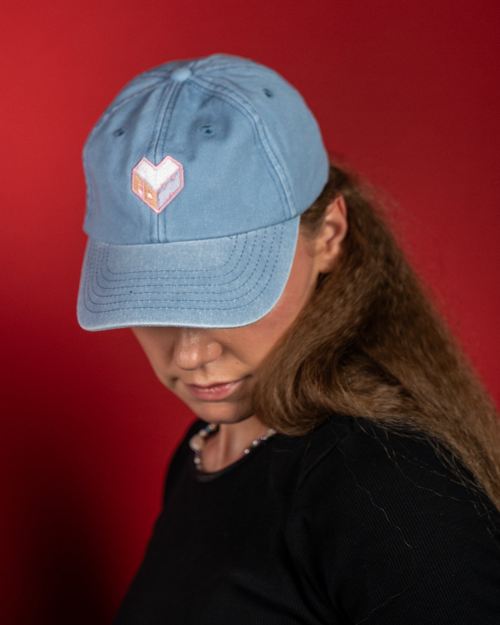 Hellblaue Baumwoll-Cap mit gesticktem Logo in Herzform auf der Vorderseite. Das Logo zeigt die Buchstaben „LFDW“ in Rosa und Weiß. Die Kappe besitzt eine leicht gebogene Krempe, sechs Belüftungslöcher und sichtbare Ziernähte für einen sportlich-lässigen Look.