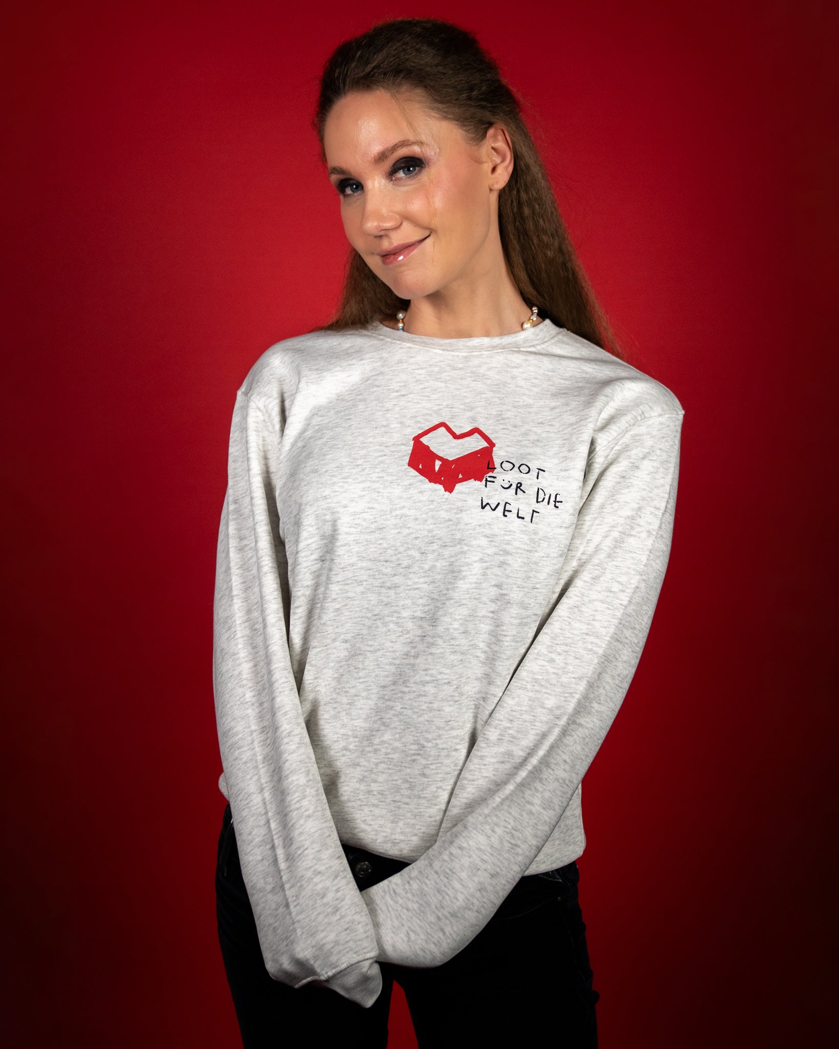 Hellgrauer Sweatshirt mit rotem Herzsymbol und schwarzem handschriftlichem Schriftzug „LOOT FÜR DIE WELT“ auf der linken Brustseite. Der Pullover hat eine lockere Passform, weichen Stoff und einen klassischen Rundhalsausschnitt, ideal für einen bequemen Alltagslook.