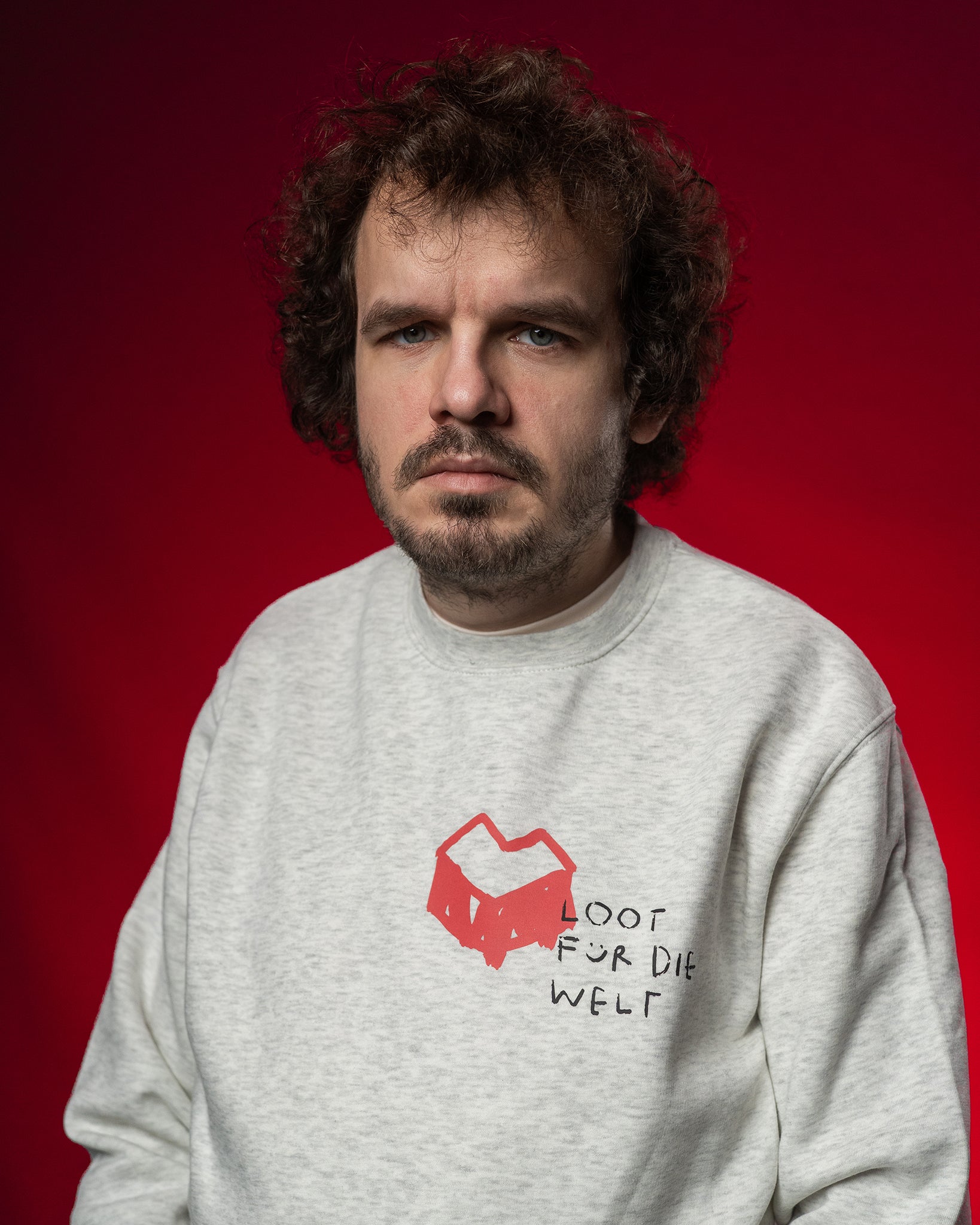 Hellgrauer Sweatshirt mit rotem, grafischem Herz-Logo und handschriftlichem Schriftzug „LOOT FÜR DIE WELT“ auf der linken Brustseite. Der Pullover besteht aus weichem Stoff, hat einen Rundhalsausschnitt und eine lockere Passform.