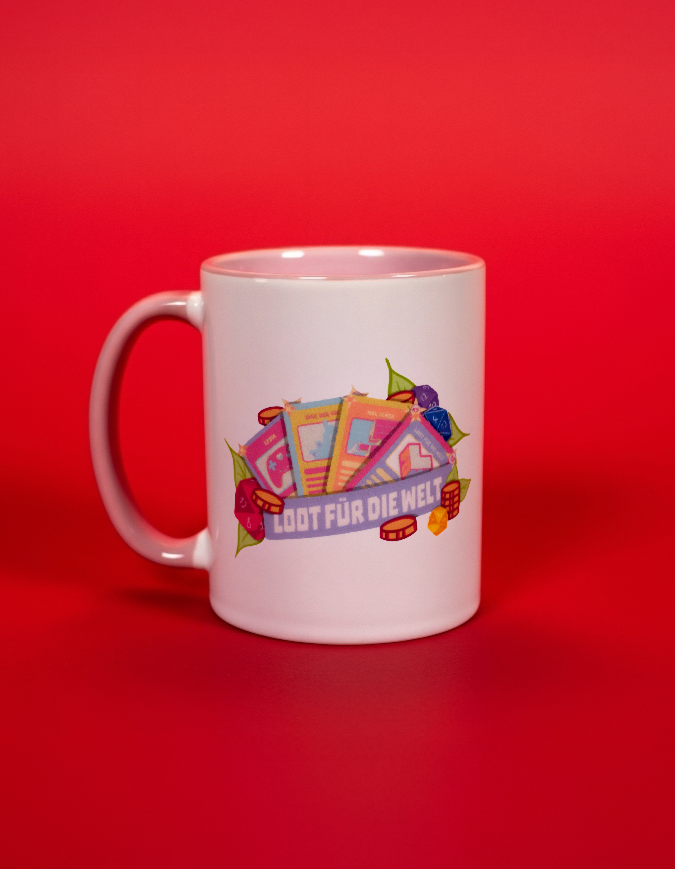 Weiße Keramiktasse mit farbenfrohem Frontprint. Das Motiv zeigt mehrere Spielkarten, Würfel und Münzen, kombiniert mit dem Schriftzug „LOOT FÜR DIE WELT“ in einem breiten Banner. Die Illustration greift Gaming- und Charity-Elemente auf und verleiht der Tasse einen verspielten, modernen Look. Die Innenseite der Tasse ist in zartem Rosa gehalten.